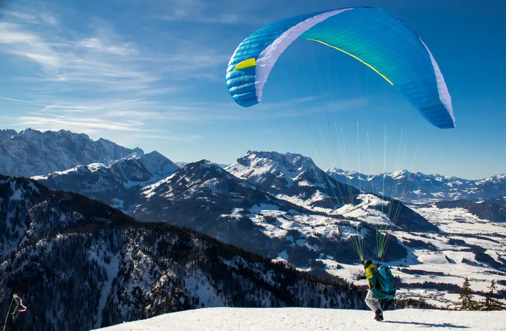 Man takes off with paraglider into a mountain panorama