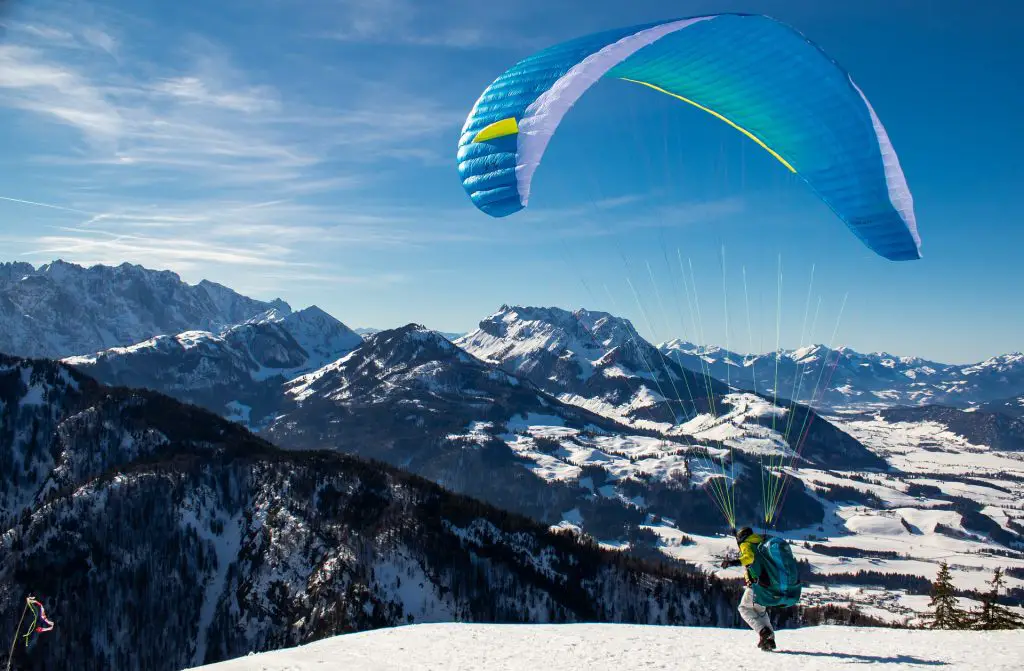 Mann startet mit dem Gleitschirm in ein Bergpanorama