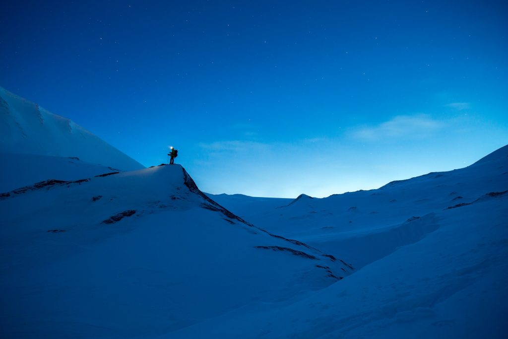 Mann steht bei Nacht in Schneelandschaft